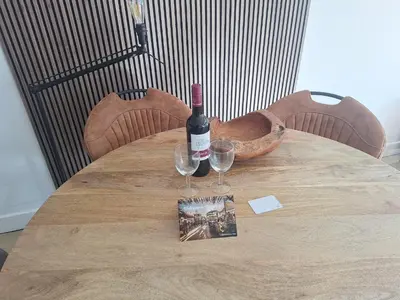 a bottle of wine and two glasses on a wooden table at Have a nice stay! - Apartment Duinvos 150m from the beach in Noordwijk aan Zee
