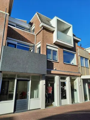 a person standing in the window of a building at Have a nice stay! - Apartment Duinvos 150m from the beach in Noordwijk aan Zee