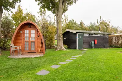a small cabin in a yard next to a tree at Tiny Camping Pod in Warmond
