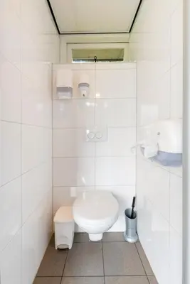 a white bathroom with a toilet and a sink at Tiny Camping Pod in Warmond