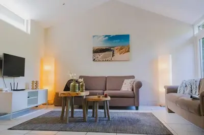 a living room with a couch and a table at Vakantiehuis Duinwald, geschikt voor 8 personen in Bergen