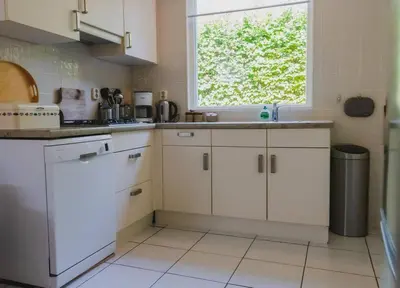 a kitchen with white cabinets and a window at Vakantiehuis Duinwald, geschikt voor 8 personen in Bergen