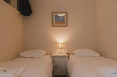 two beds in a room with a lamp on a table at Vakantiehuis Duinwald, geschikt voor 8 personen in Bergen
