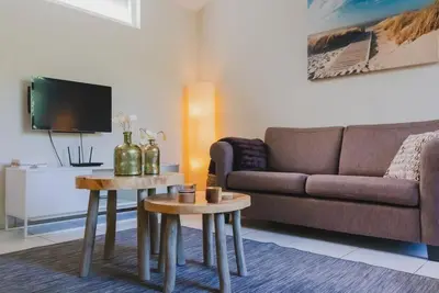 a living room with a couch and two tables at Vakantiehuis Duinwald, geschikt voor 8 personen in Bergen