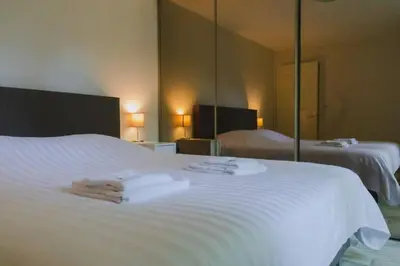 a hotel room with a white bed with mirrors at Vakantiehuis Duinwald, geschikt voor 8 personen in Bergen