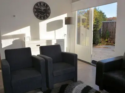 a living room with two chairs and a clock on the wall at Duinnest in Noordwijkerhout