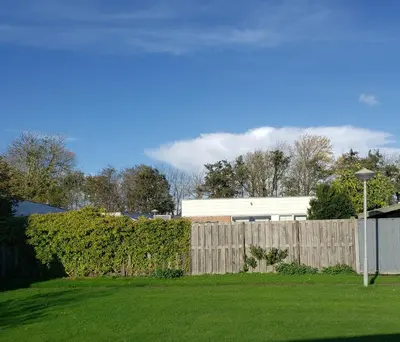 a wooden fence in a yard with a building at Duinnest in Noordwijkerhout