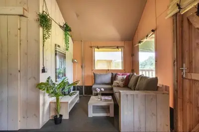 a living room in a tiny house with a couch and a table at Glamping lodge with Eco-Wellness in Zeewolde