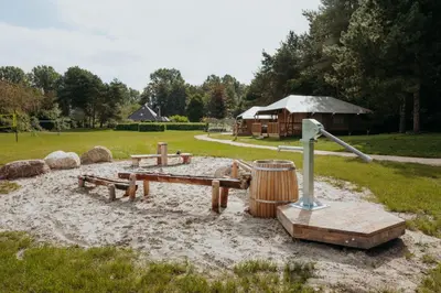 a park with a picnic table and a wooden barrel at Glamping lodge with Eco-Wellness in Zeewolde