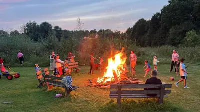 a group of people around a fire in a field at Glamping lodge with Eco-Wellness in Zeewolde