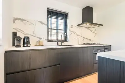 a kitchen with brown cabinets and a sink and a window at Goudkust 4 'Schoorls Geluk' in Schoorl