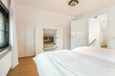 a white bedroom with a bed and a tv at Goudkust 4 'Schoorls Geluk' in Schoorl