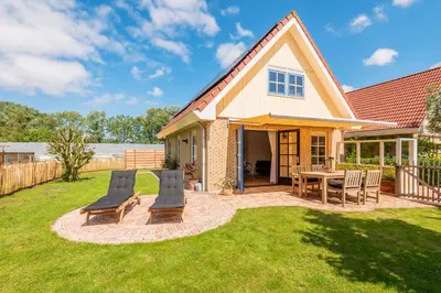 a house with a patio and a table and chairs at Goudkust 4 'Schoorls Geluk' in Schoorl