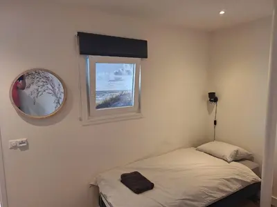 a small bedroom with a bed and a mirror at Have a nice stay! - Silt14 Sfeervol vakantie appartement in Noordwijk