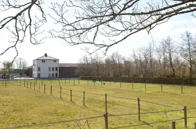 a field with a fence and a white building at Have a nice stay! - Silt14 Sfeervol vakantie appartement in Noordwijk