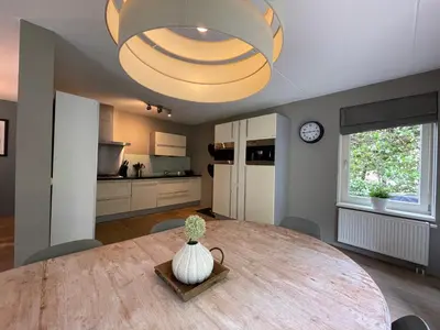 a kitchen and dining room with a large wooden table at VILLA CALMA Rust Ruimte Luxe inclusief private jacuzzi in Zeewolde