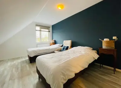 a bedroom with two beds and a blue wall at VILLA CALMA Rust Ruimte Luxe inclusief private jacuzzi in Zeewolde
