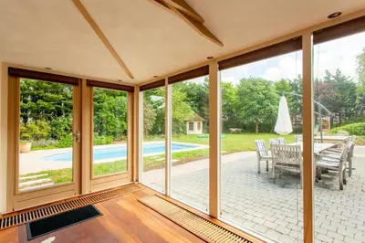 a conservatory with sliding glass doors and a table and chairs at 13P 5B Beautiful villa with heated Pool and Jacuzzi in Heerhugowaard
