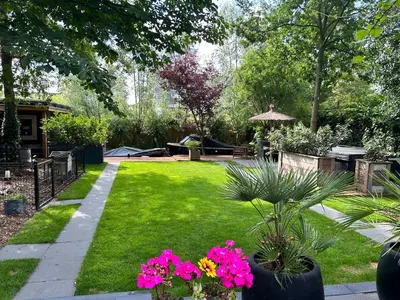 a garden with pink flowers in a yard at Casa aan de Plas, B&B met sauna en hottub of jacuzzi in Nieuwkoop