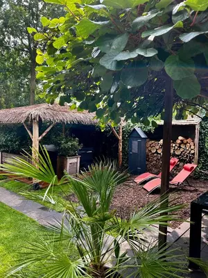 a garden with a hut with a bench and a chair at Casa aan de Plas, B&B met sauna en hottub of jacuzzi in Nieuwkoop