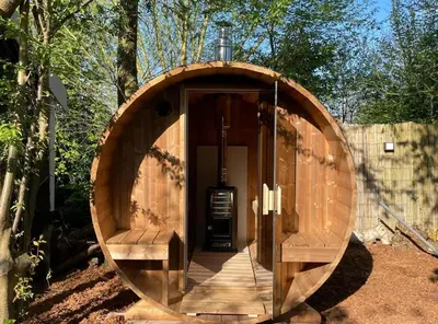a wooden circle shaped building with a door and benches at Casa aan de Plas, B&B met sauna en hottub of jacuzzi in Nieuwkoop