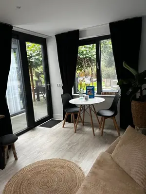a living room with a table and chairs and windows at Casa aan de Plas, B&B met sauna en hottub of jacuzzi in Nieuwkoop