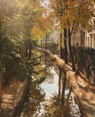 a woman walking along a river in a city at Vlinder's in Utrecht