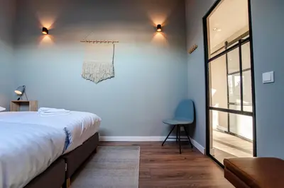 a bedroom with a bed and a blue chair at Spacious Luxury Loft in Zandvoort