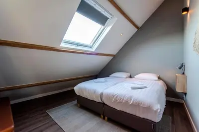 a bedroom with a bed in a attic with a window at Spacious Luxury Loft in Zandvoort