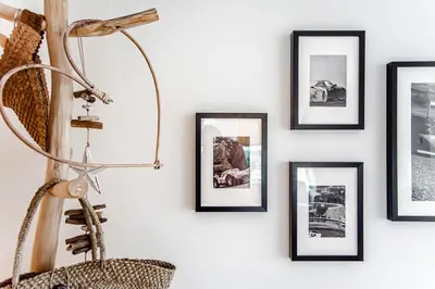 a wall with framed pictures on a wall with a lamp at South Beach House in Zandvoort