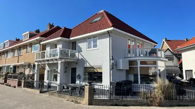 a white house with a red roof on a street at South Beach House in Zandvoort