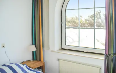 a bedroom with a window and a bed and a lamp at Bellevue in Bergen aan Zee