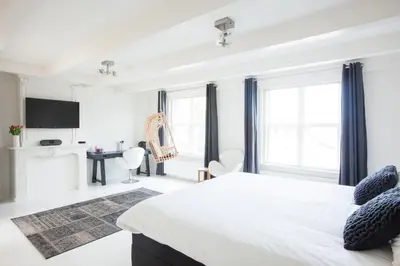 a white bedroom with a large bed and a desk at Mokum Suites in Amsterdam