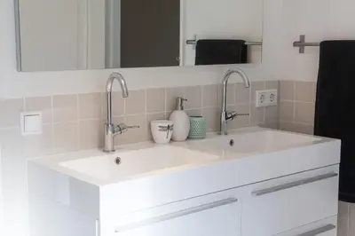 a white bathroom with two sinks and a mirror at Mokum Suites in Amsterdam