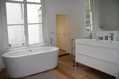 a white bathroom with a large tub and a window at Mokum Suites in Amsterdam