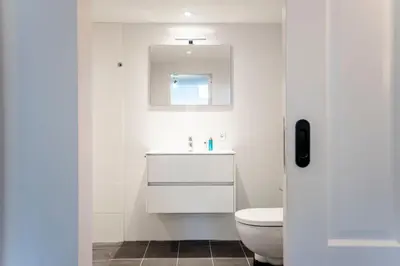 a white bathroom with a toilet and a sink at Casa Beach with free parking and garden in Zandvoort