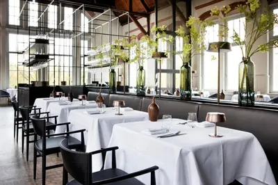 a row of tables in a restaurant with vases with flowers at Pillows Grand Boutique Hotel Maurits at the Park - Small Luxury Hotels in Amsterdam