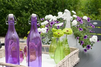 four purple glass bottles sitting on a table with flowers at Mariahoeve-Logies #Polderhuisje in Woubrugge