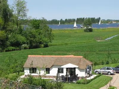 a white house in a field with boats in the water at Mariahoeve-Logies #Polderhuisje in Woubrugge