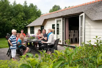 a group of people sitting around a table on a patio at Mariahoeve-Logies #Polderhuisje in Woubrugge