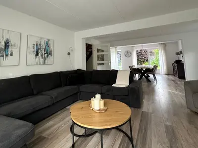 a living room with a black couch and a table at Big Family villa 12p big garden with bathtub and jacuzzi in Zeewolde