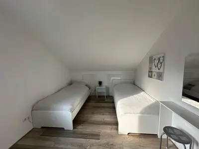 two beds in a room with white walls and wooden floors at Big Family villa 12p big garden with bathtub and jacuzzi in Zeewolde