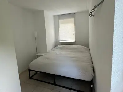 a small bed in a small room with a window at Big Family villa 12p big garden with bathtub and jacuzzi in Zeewolde