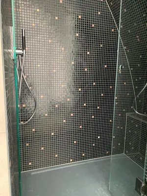 a shower with a black tiled wall at Penthouse Witsand Zeezicht in Egmond aan Zee