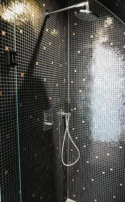 a bathroom with a shower with a black tiled wall at Penthouse Witsand Zeezicht in Egmond aan Zee