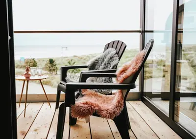 a black rocking chair with a faux fur seat and a table at Penthouse Witsand Zeezicht in Egmond aan Zee