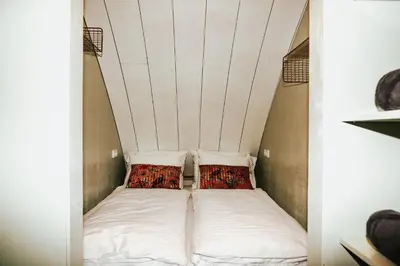 a bed in a small room with two pillows at Penthouse Witsand Zeezicht in Egmond aan Zee