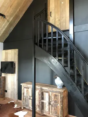 a spiral staircase in a room with a wooden table at Logement Bilderdam in Leimuiden