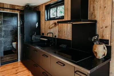 a kitchen with a black counter and a sink at Logement Bilderdam in Leimuiden