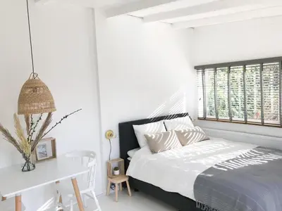 a white bedroom with a bed and a window at Little Beach House in Zandvoort